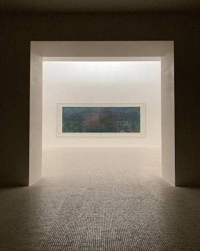 Dark doorway opening into a bright room with a long horizontal painting on a white wall and a textured floor.