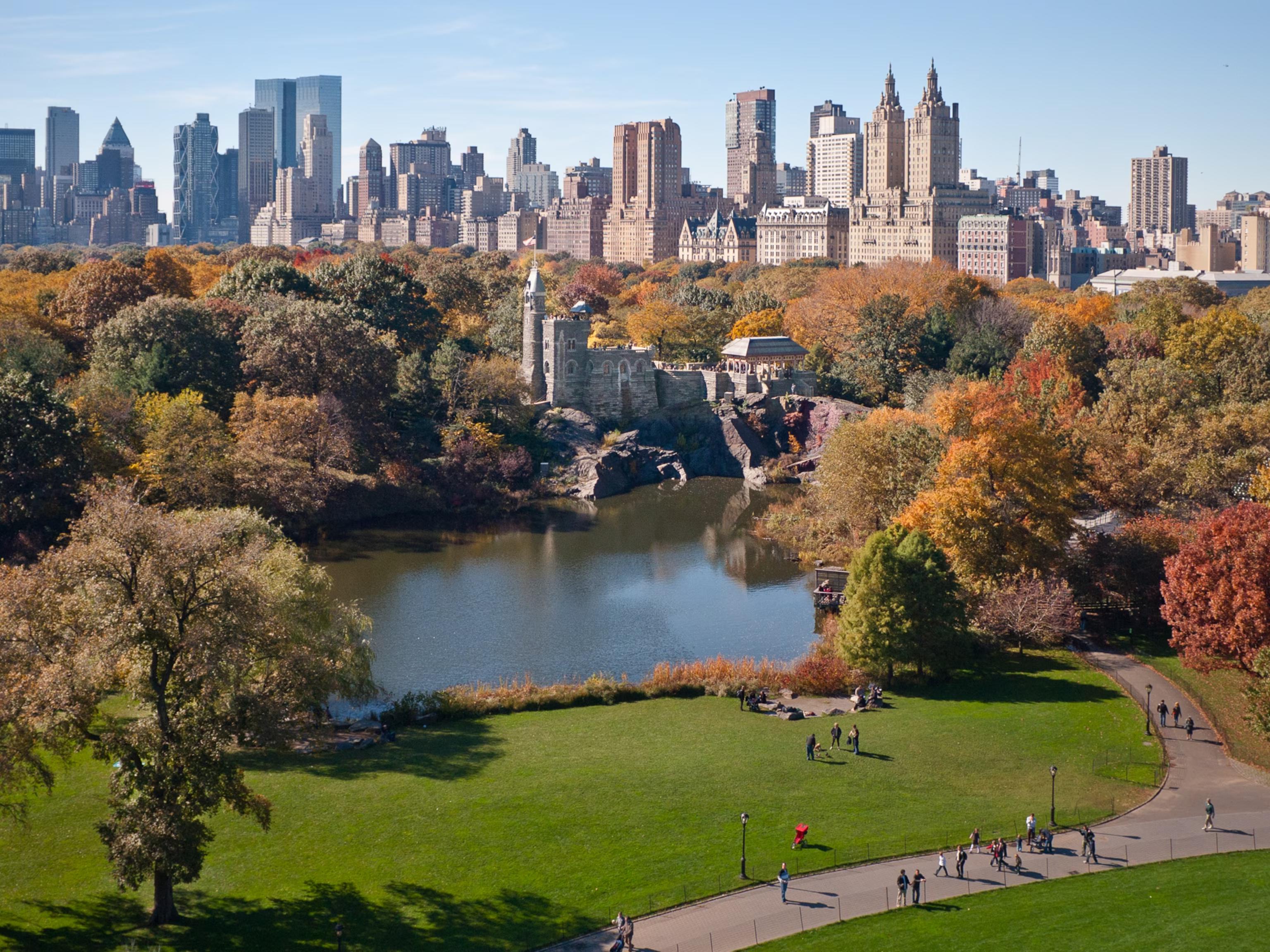 Autumn view of Central Park with Belvedere Castle, a lake, and the NYC skyline.