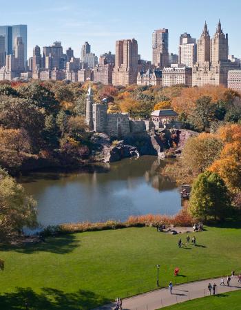 Autumn view of Central Park with Belvedere Castle, a lake, and the NYC skyline.