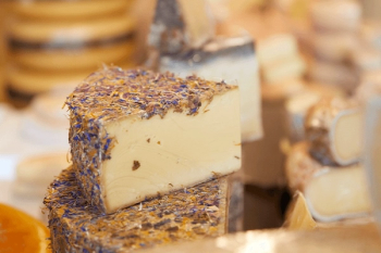 A wedge of cheese covered in dried blue and yellow flowers.