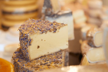 A wedge of cheese covered in dried blue and yellow flowers.