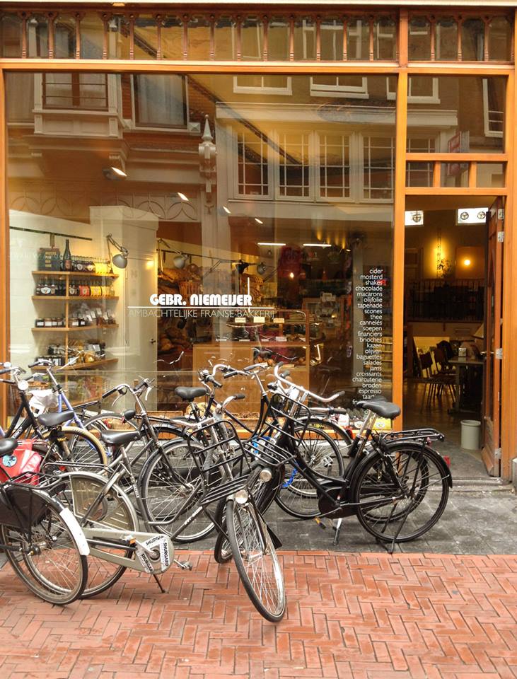 Many bicycles parked in front of Gebr. Niemeijer Artisanal French Bakery.