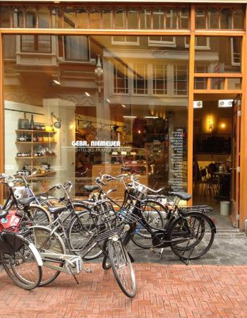 Many bicycles parked in front of Gebr. Niemeijer Artisanal French Bakery.