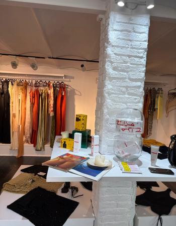 Interior of a clothing boutique with a white display table showcasing various items and racks of colorful clothing.
