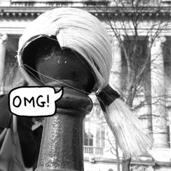 Black and white photo of a blonde wig on a black pole, with a speech bubble saying "OMG!".
