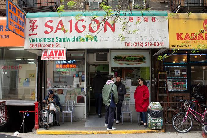 A Saigon Vietnamese Sandwich (Banh Mi) shop with people standing outside on a city street.