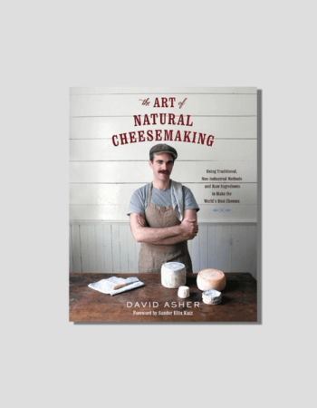 Book cover for "The Art of Natural Cheesemaking" by David Asher, showing the author in an apron with various cheeses on a wooden table.
