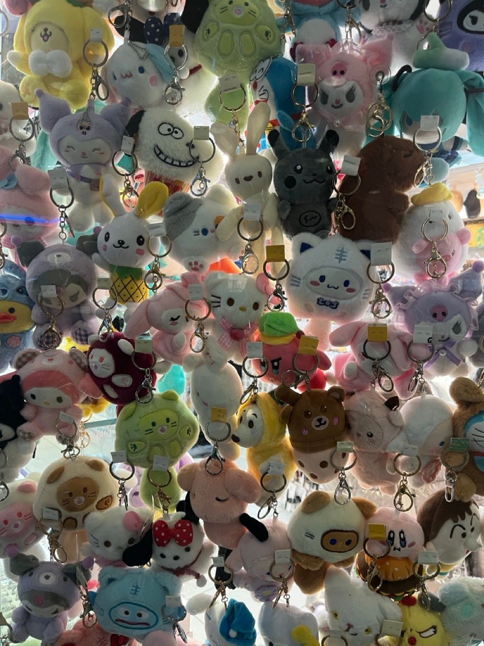 A dense collection of colorful plush cartoon character keychains hanging together.