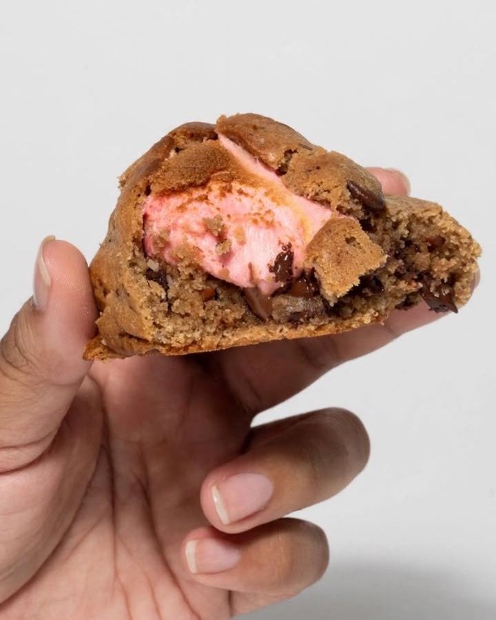 Galleta de chocolate partida mostrando un relleno cremoso de fresa