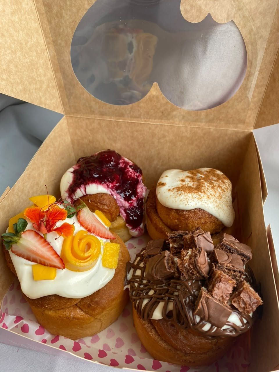 Caja con cuatro roles de canela de distintos sabores y toppings