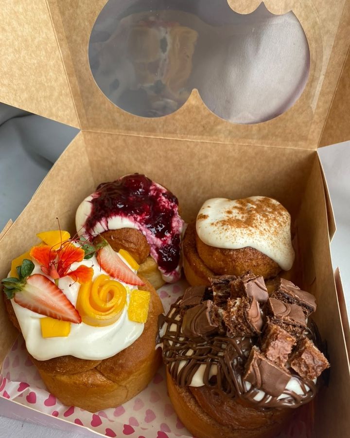 Caja con cuatro roles de canela de distintos sabores y toppings