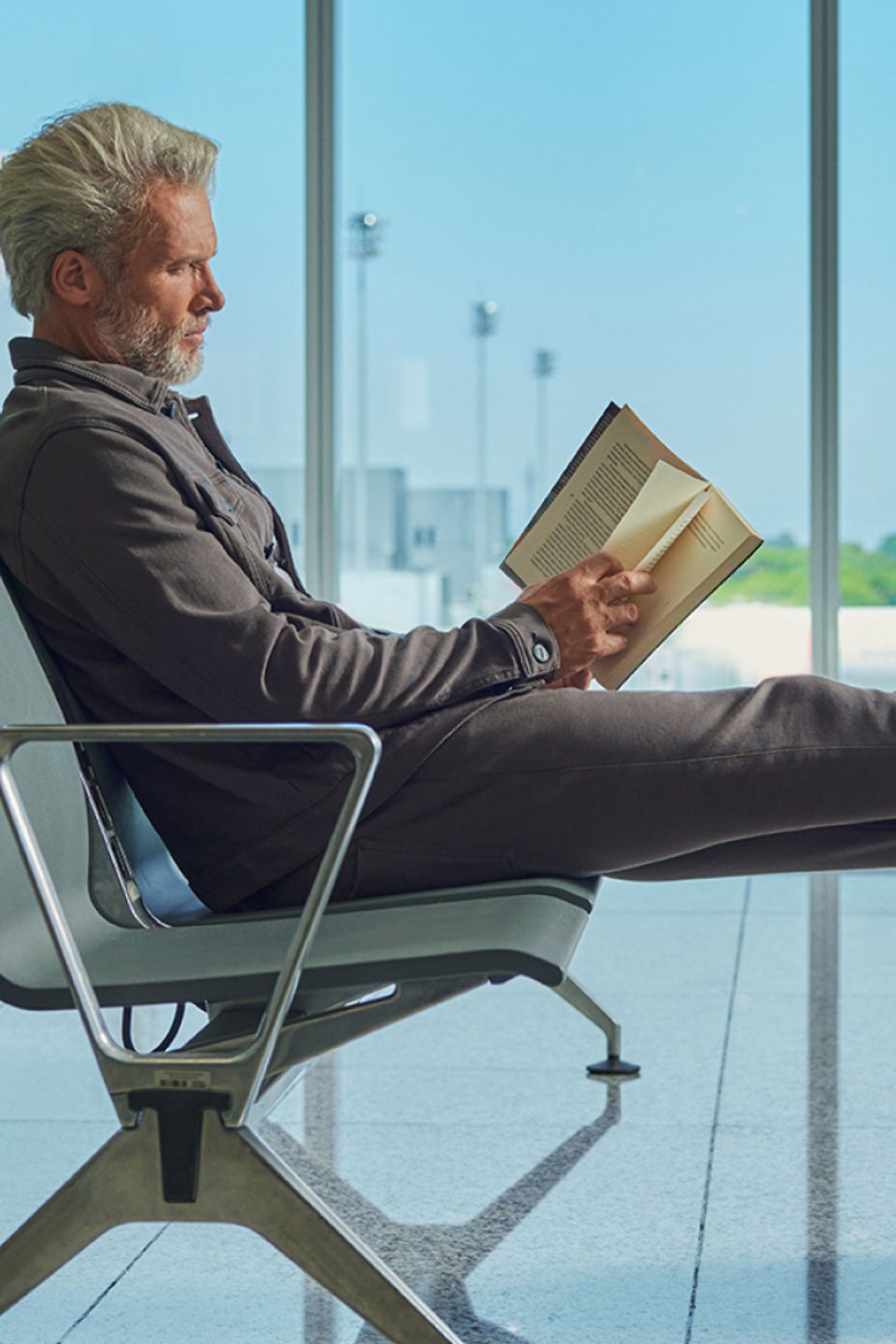 Homem lendo livro no aeroporto usando linha 247 da Oficina
