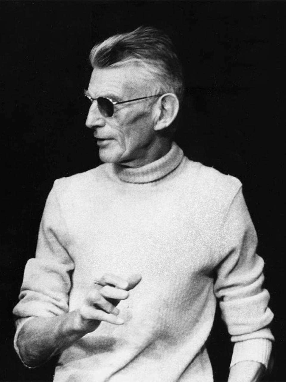 Samuel Beckett usando roupas de alfaitaria com um suéter gola alta