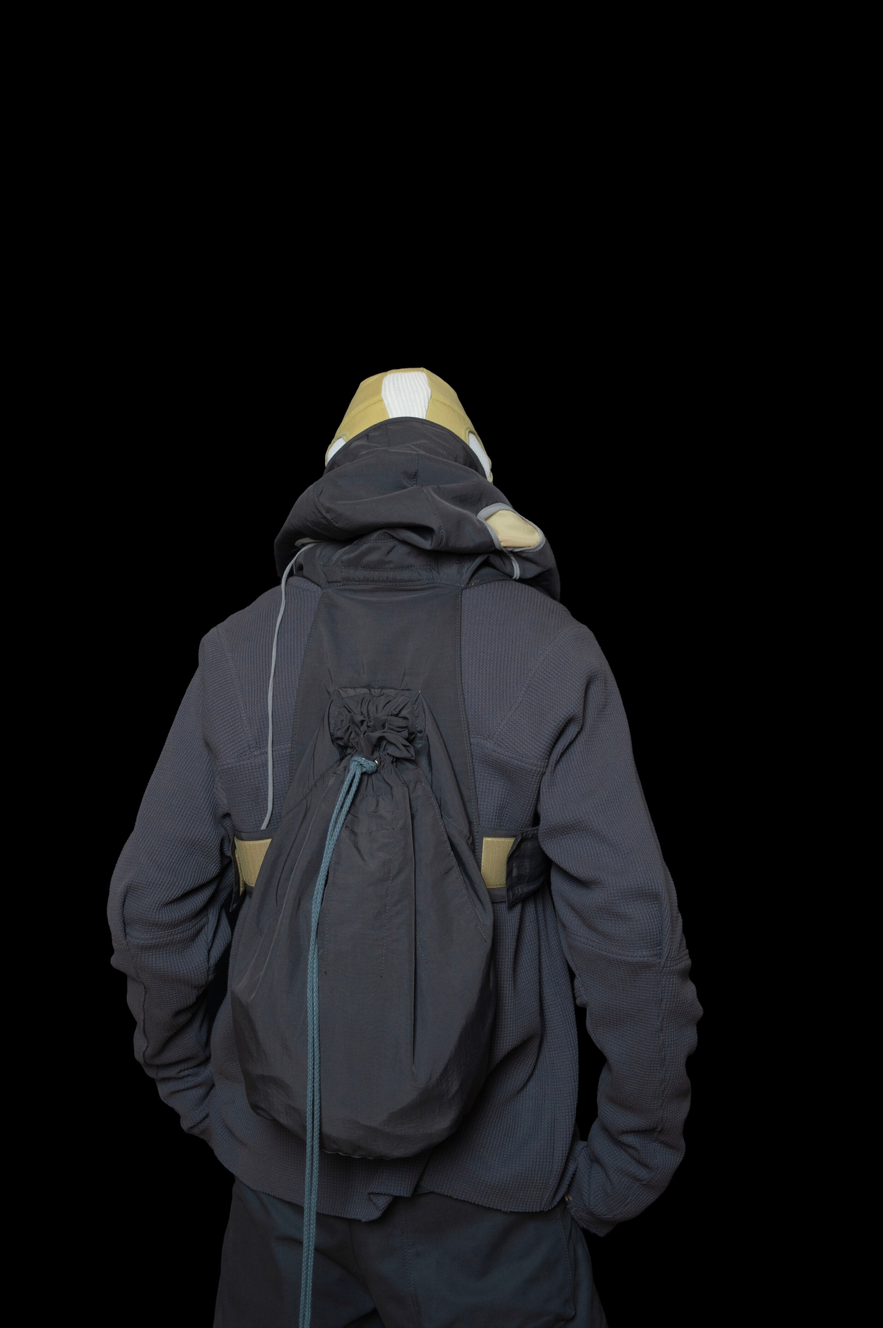 back view of man wearing head liner cap, oxygen hooded vest bag, thermal jumper, and layered trouser from bryan jimenez fall winter 2020