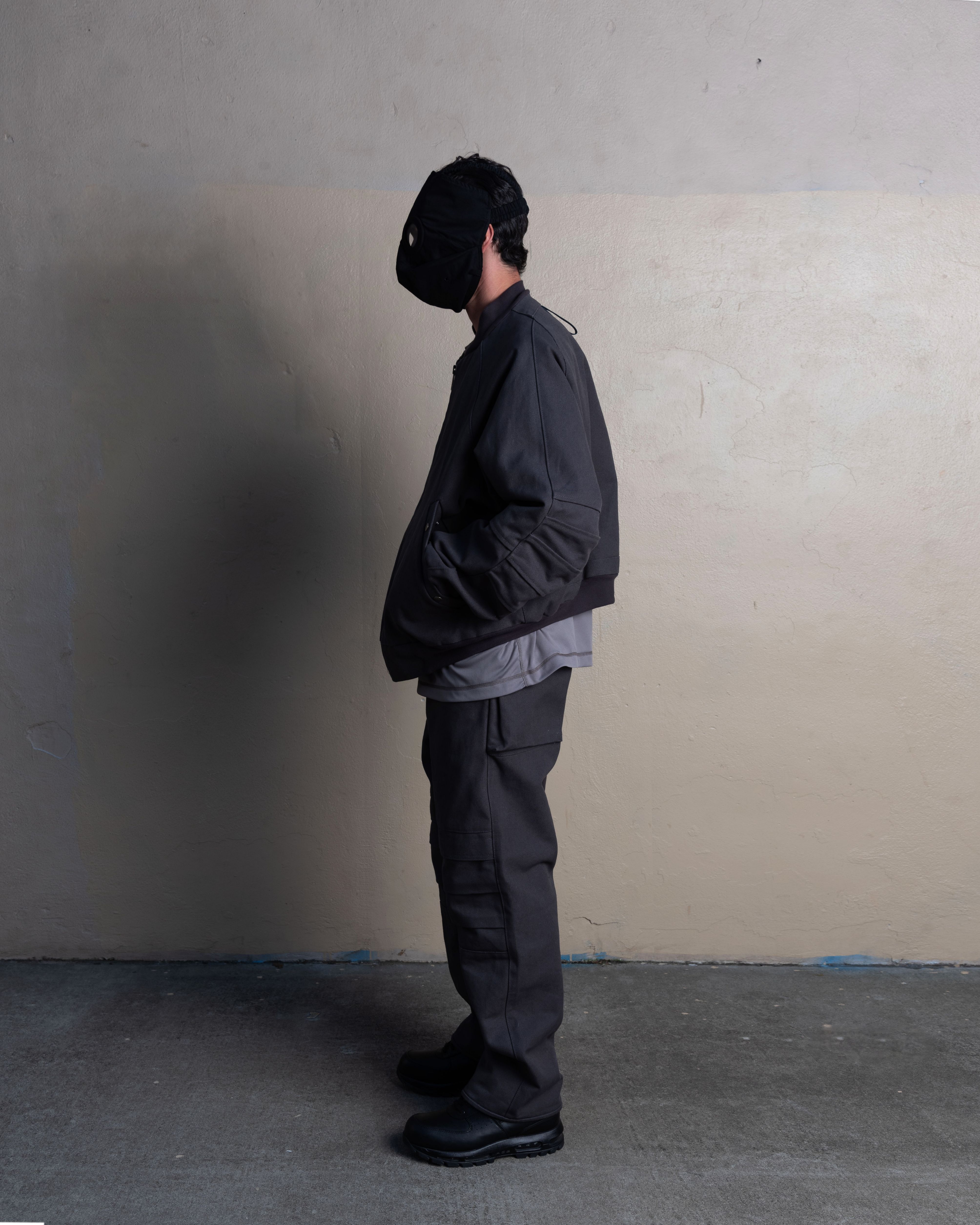 profile view of man wearing rocket conductor mask, lunar bomber, and knee cargo trousers from bryan jimenez spring summer 2023