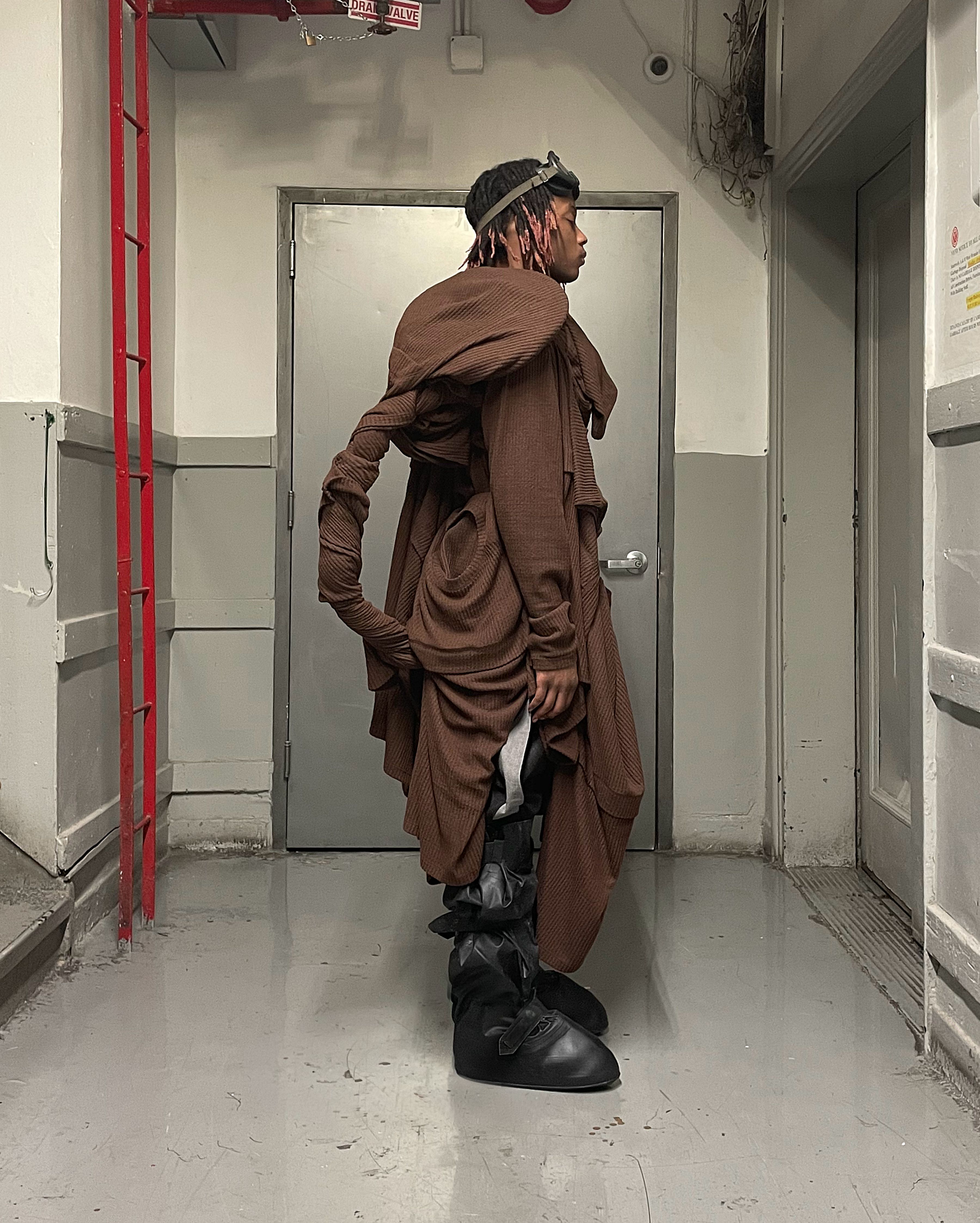 back view of man wearing cover boots and a configuration of tissue sweaters form bryan jimenez spring summer 2022