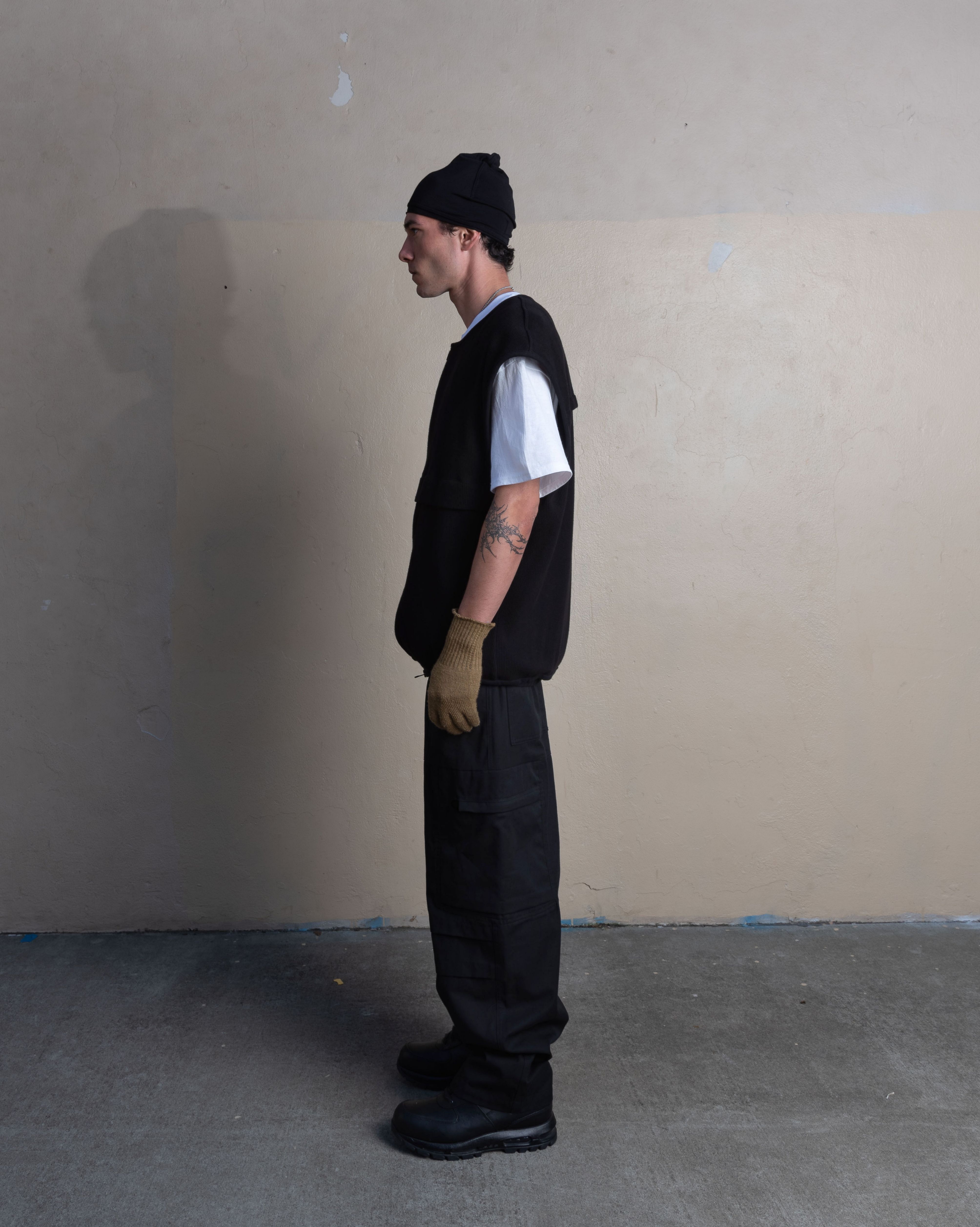 profile view of man wearing bias taped skullcap, ventilation vest, and station trousers from bryan jimenez spring summer 2023