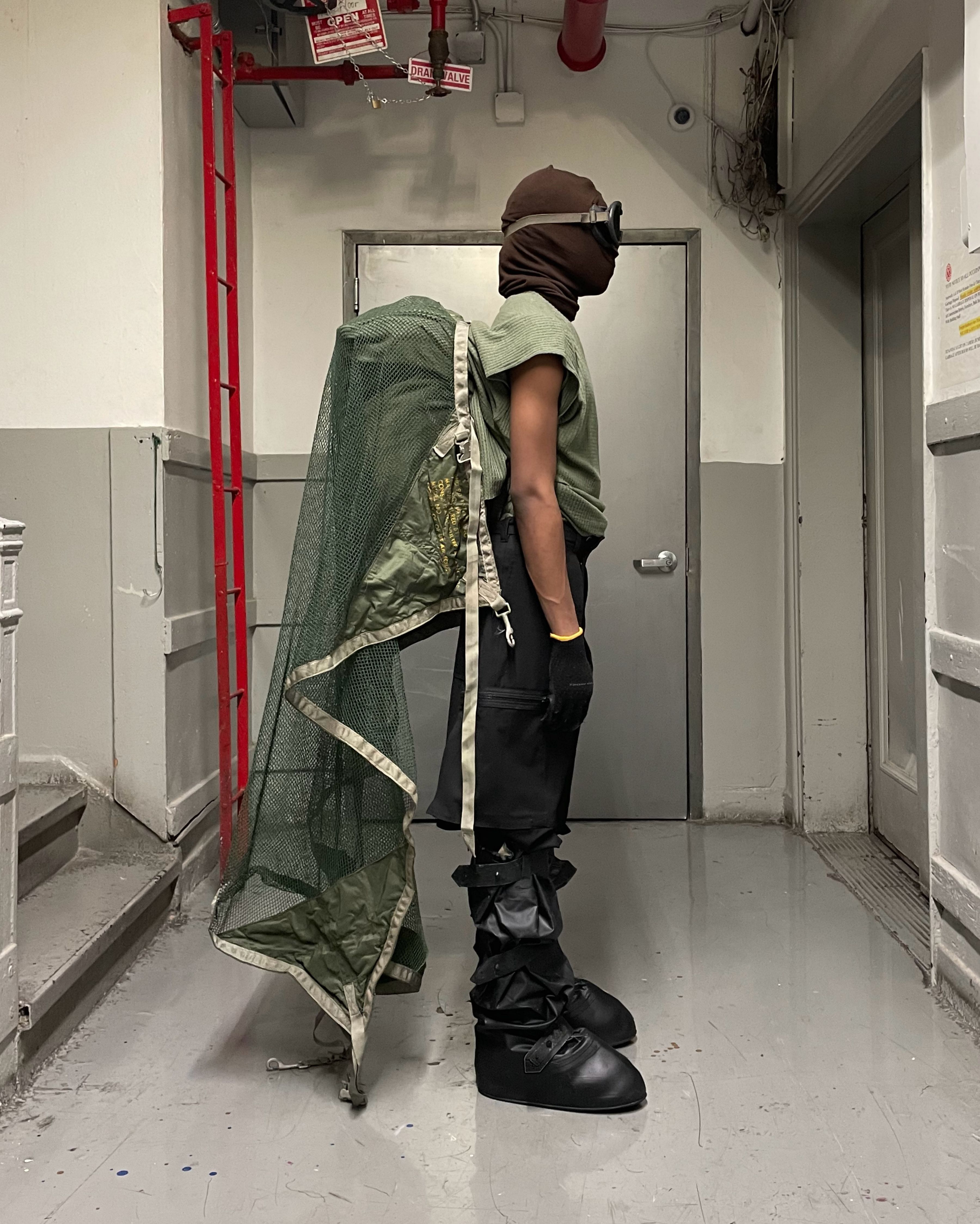 profile view of man wearing headscarf v2, uniform trousers, and cover boots from bryan jimenez spring summer 2022