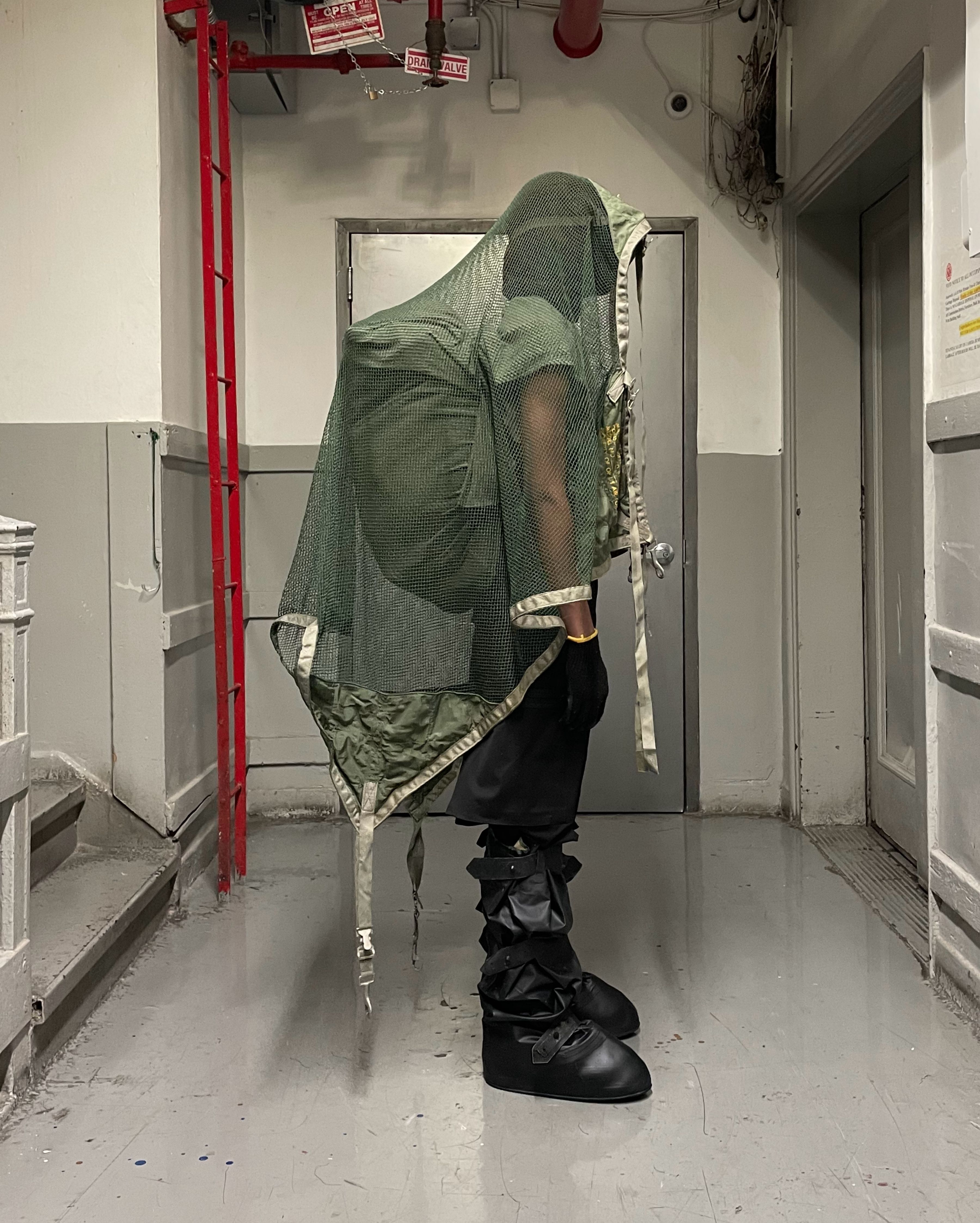 profile view of man wearing headscarf v2, uniform trousers, and cover boots from bryan jimenez spring summer 2022