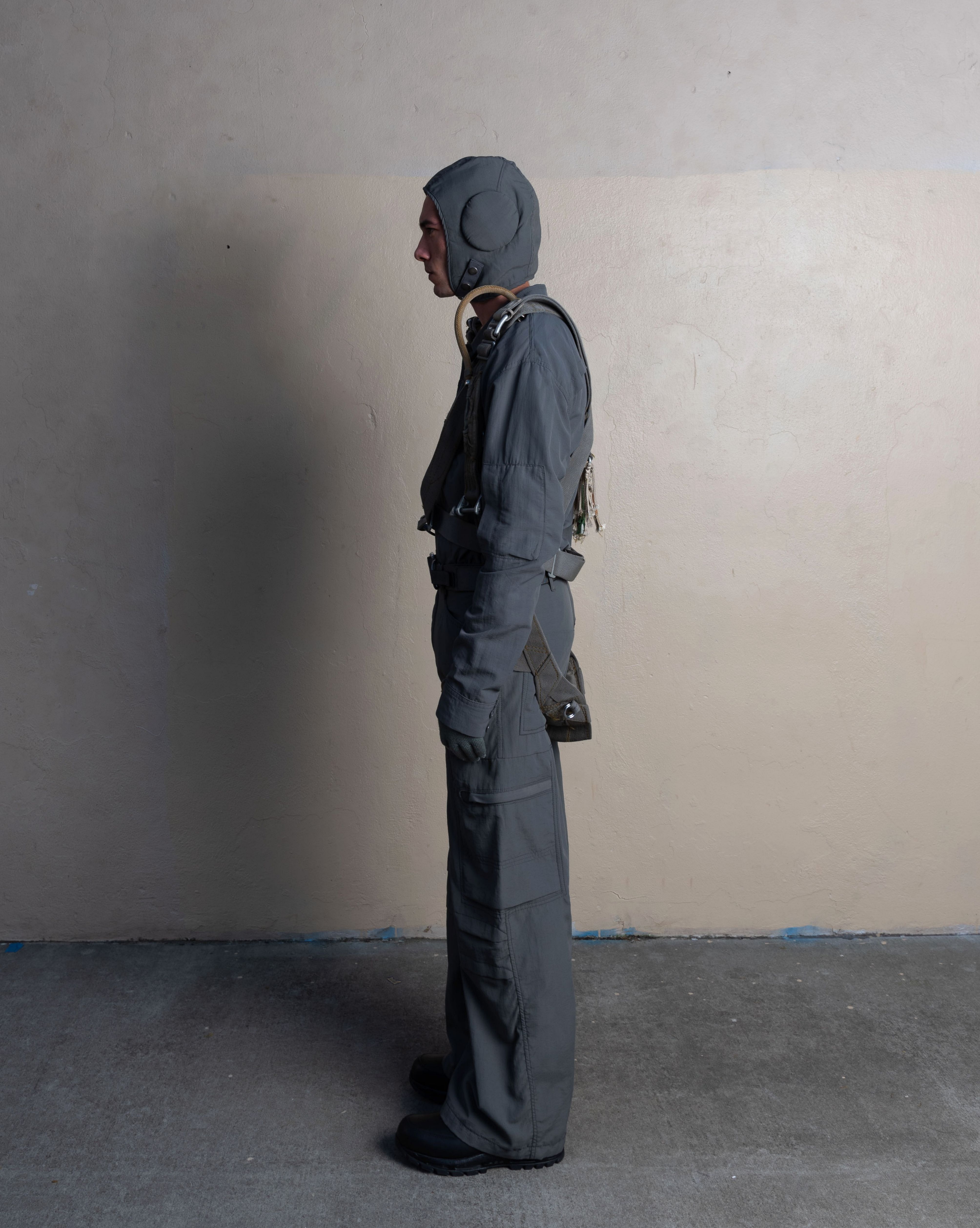 profile view of man wearing flyer helmet, pilot shirt, and station trousers from bryan jimenez spring summer 2023