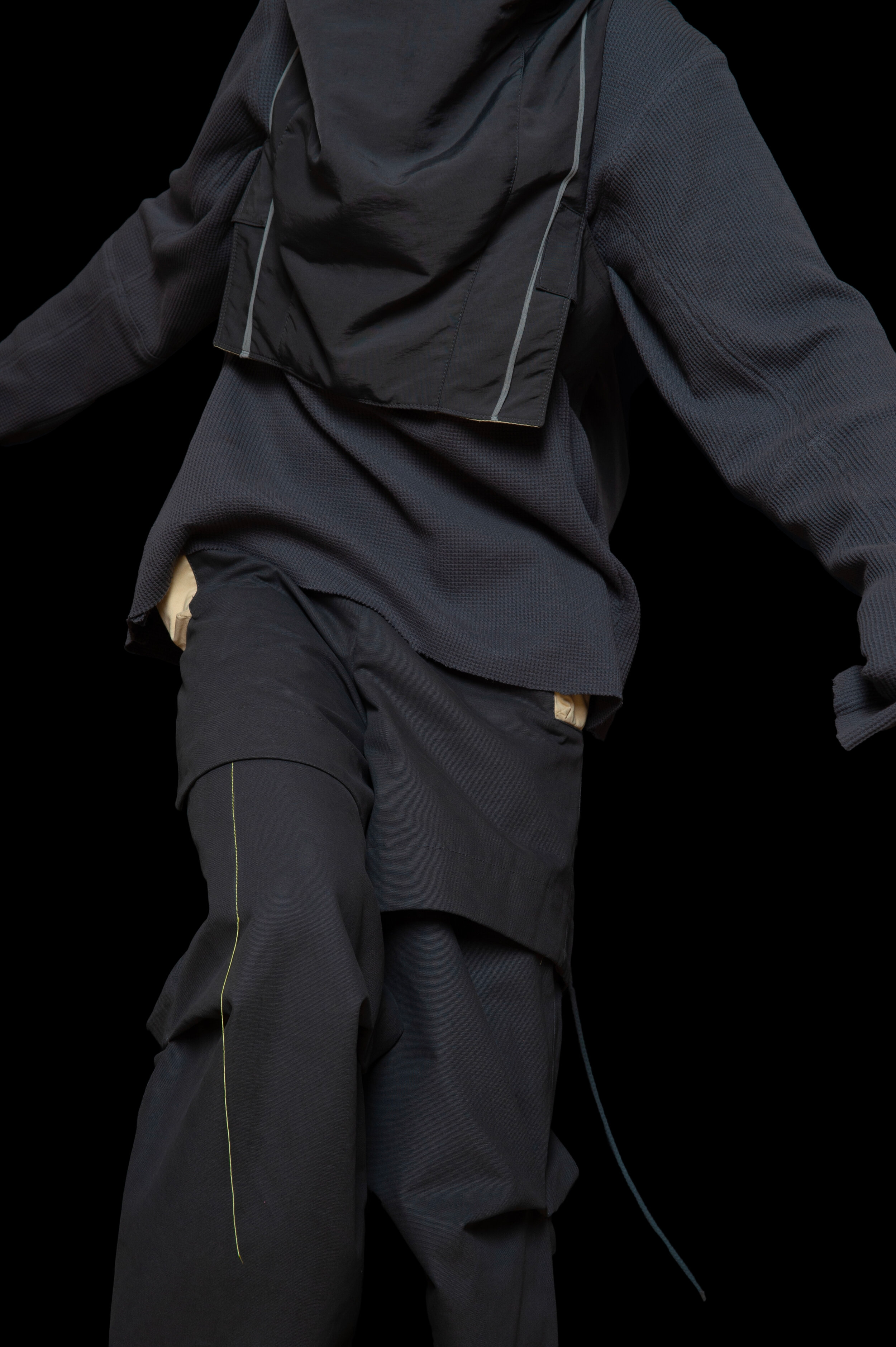 detail view of man wearing head liner cap, oxygen hooded vest bag, thermal jumper, and layered trouser from bryan jimenez fall winter 2020