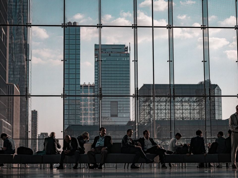 Professionisti seduti nell'atrio vetrato del Javits Center di New York, con i grattacieli di Manhattan sullo sfondo