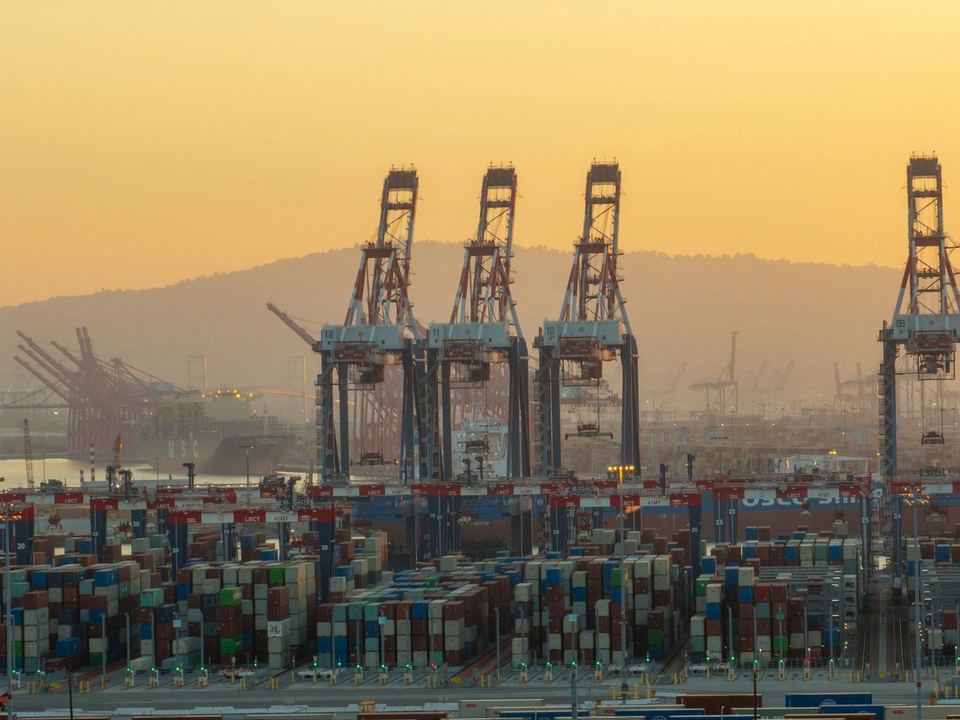 Gru portuali e container impilati nel porto di Long Beach, in California, al tramonto