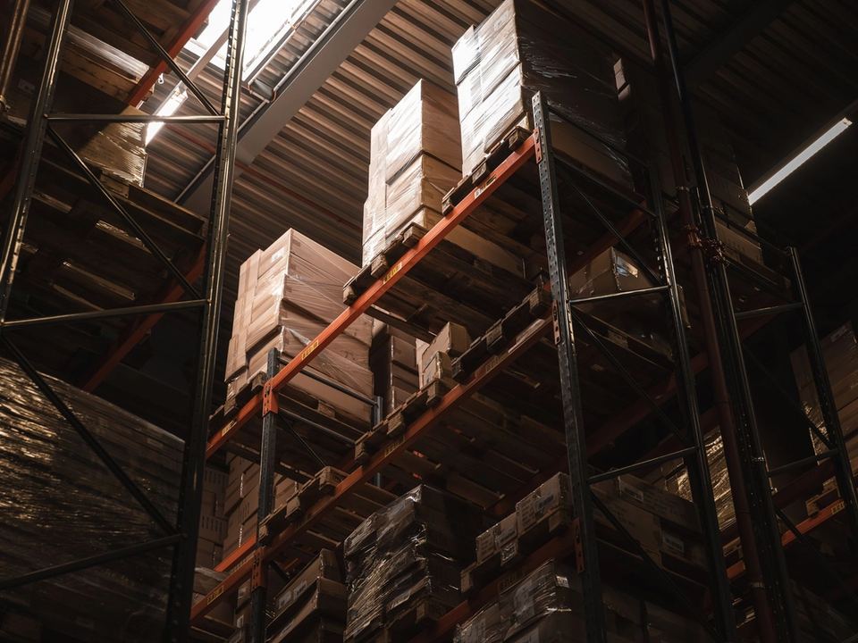 Scaffalature di un magazzino con pallet di cartoni impilati e avvolti nel film, viste dal basso