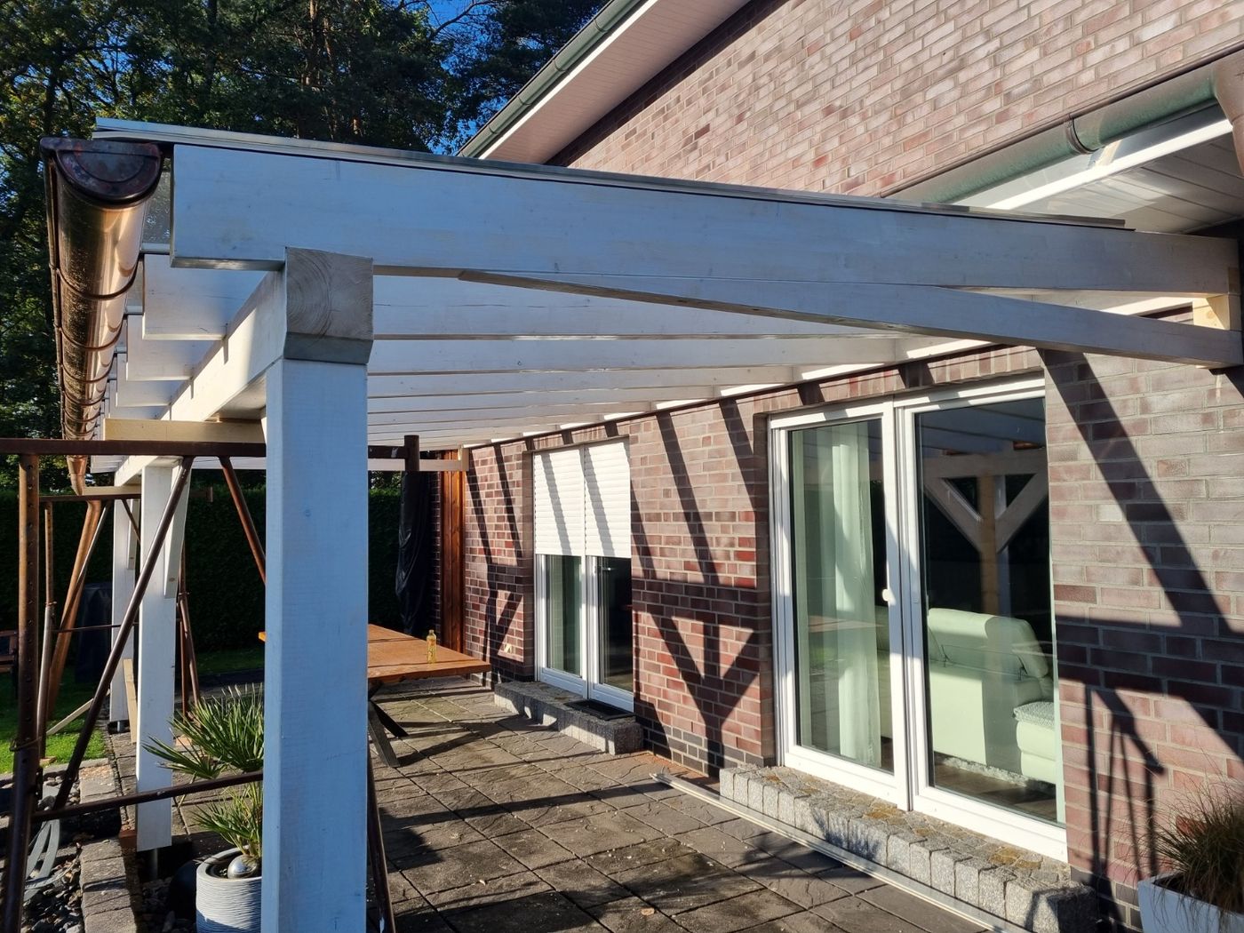 Helle Holzkonstruktion einer Terrassenüberdachung mit montierten Dachsparren und sichtbaren Holzverbindungen.