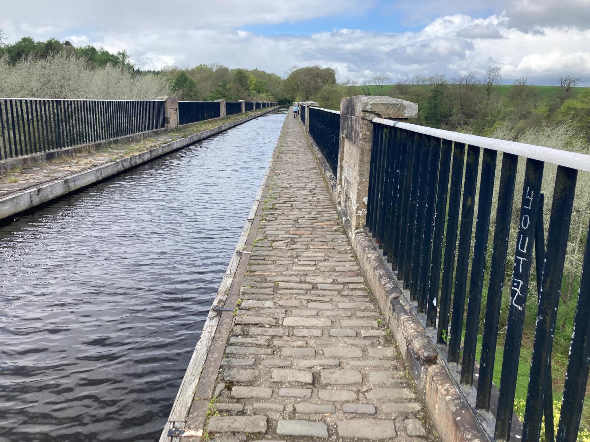 Walker following a canal towpath on the John Muir Way.