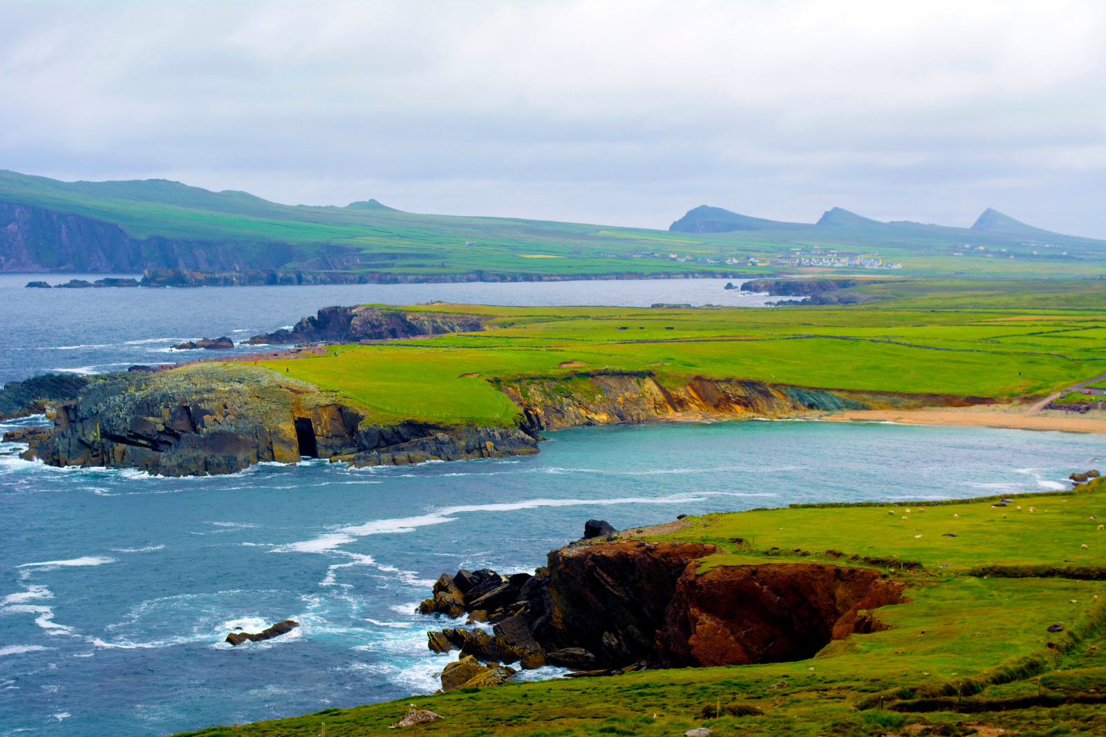 Green coastal headlands and the Three Sisters peaks on the Dingle Peninsula.