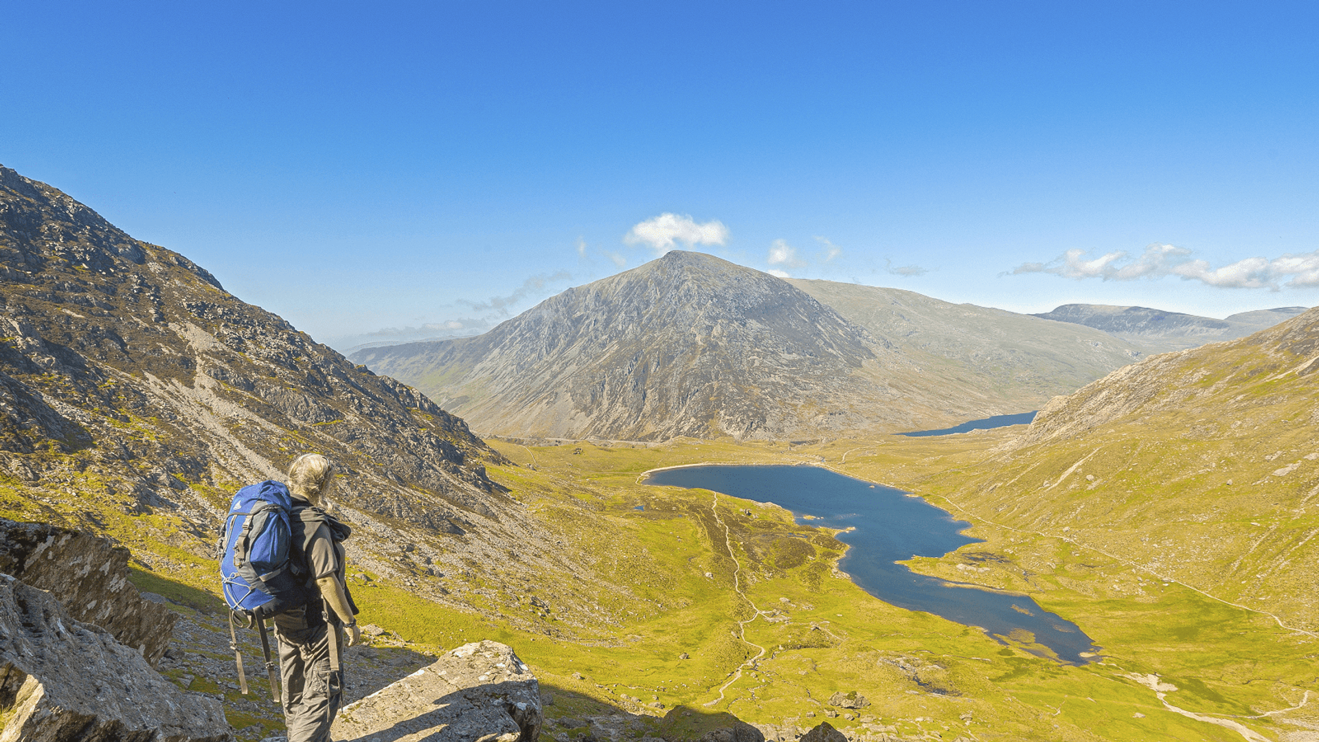 Walker on path down from devils Kitchen to Cwm Idwal with Llyn Idwal and Pen yr Ole Wen in shot