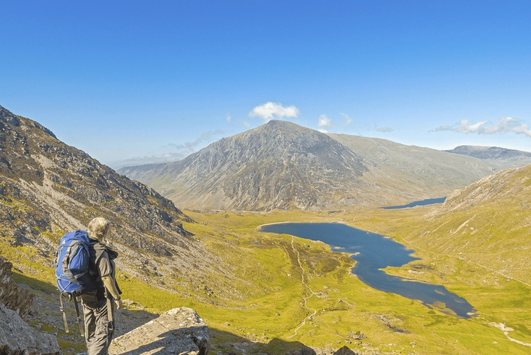 Walker on path down from devils Kitchen to Cwm Idwal with Llyn Idwal and Pen yr Ole Wen in shot