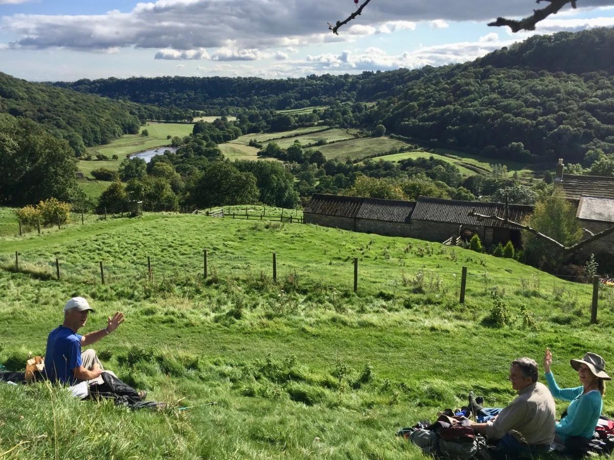 Walkers resting with views across green countryside on the Coast to Coast Walk