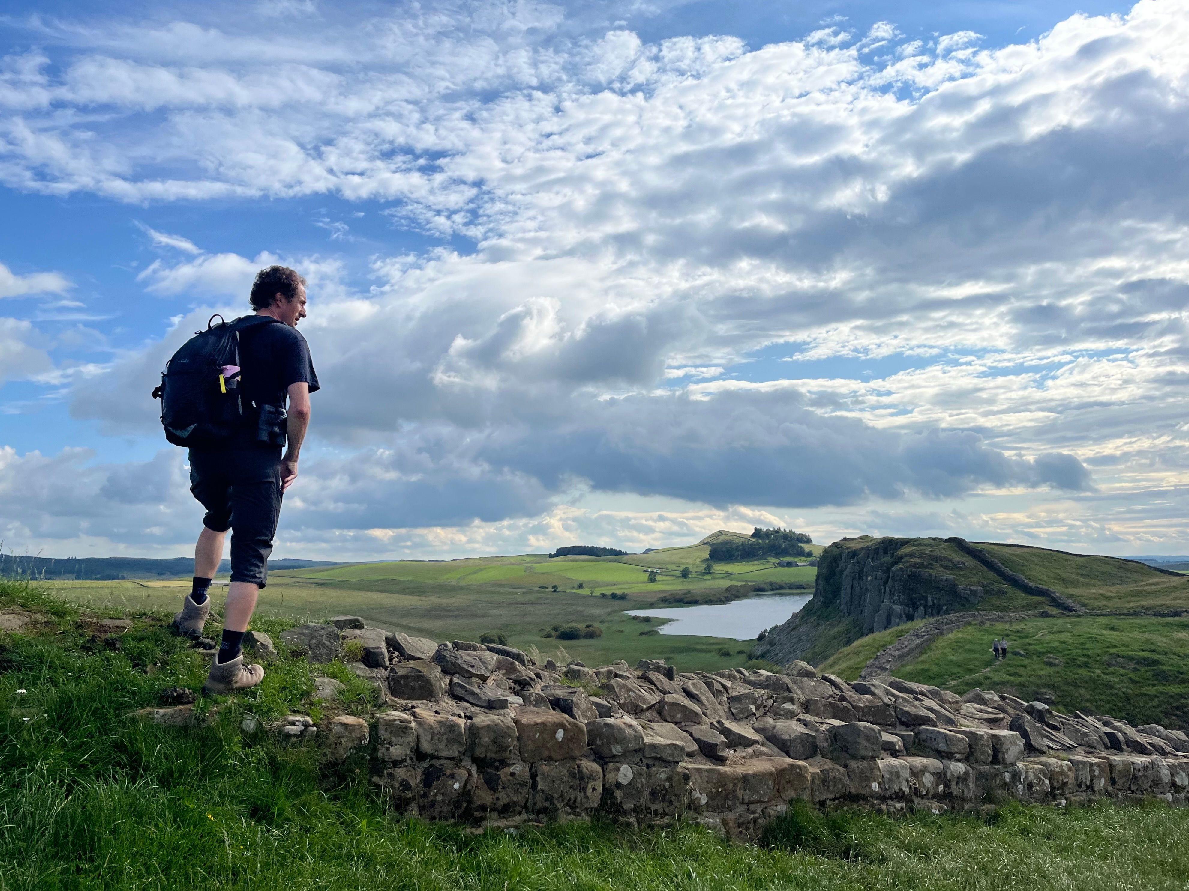 Walker overlooking Crag Lough and Hadrian's Wall on the full route through Northumberland