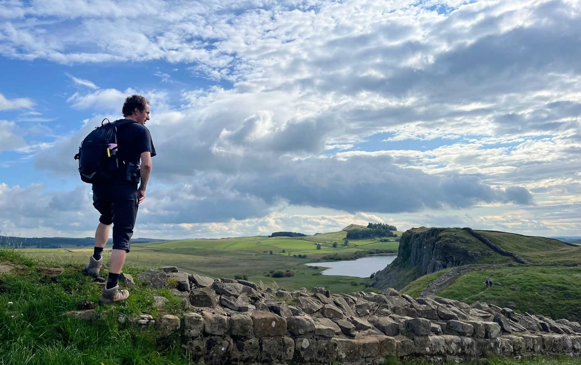 Walker overlooking Crag Lough and Hadrian's Wall on the full route through Northumberland