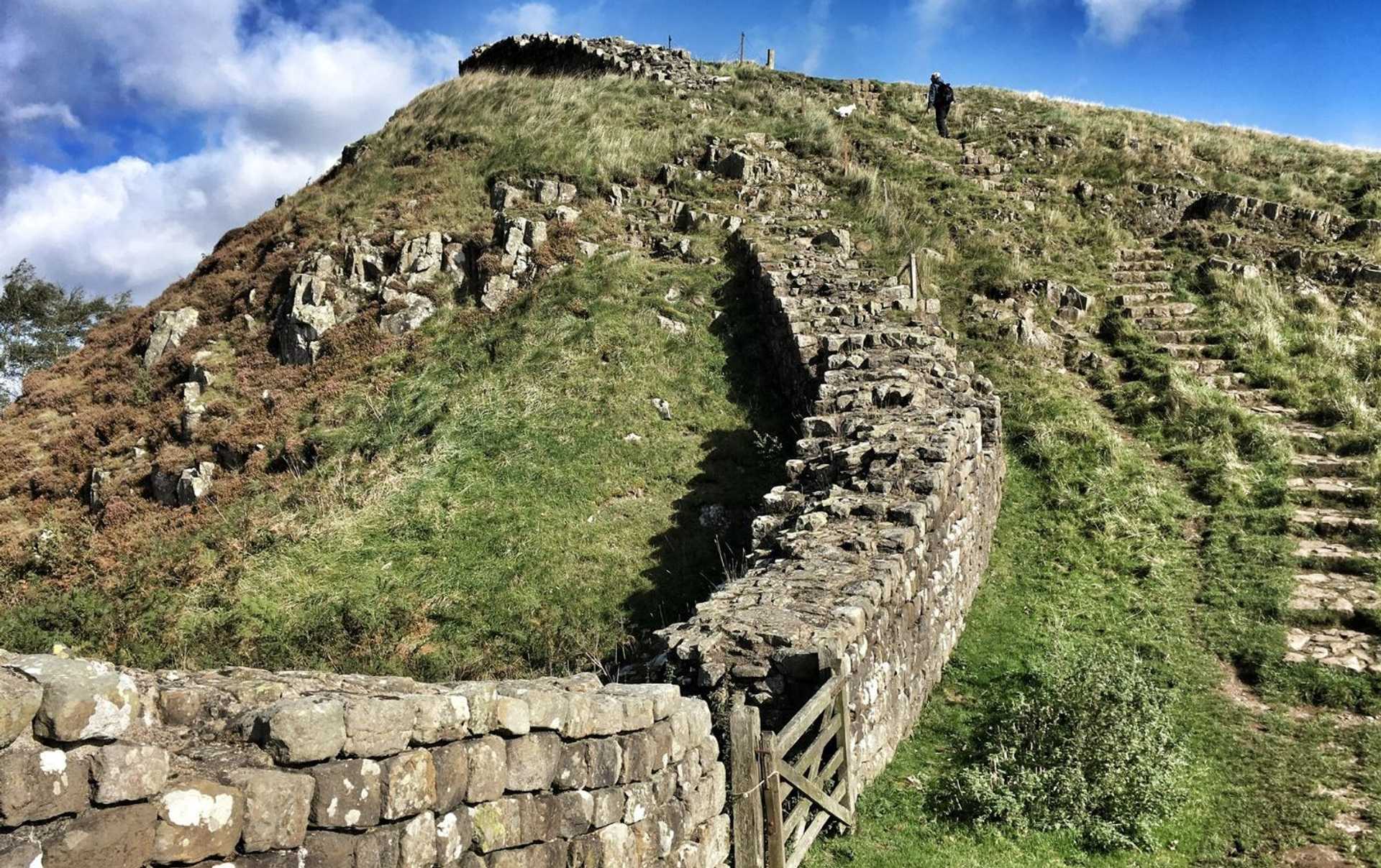Walker following Hadrian's Wall through the dramatic central section near Housesteads