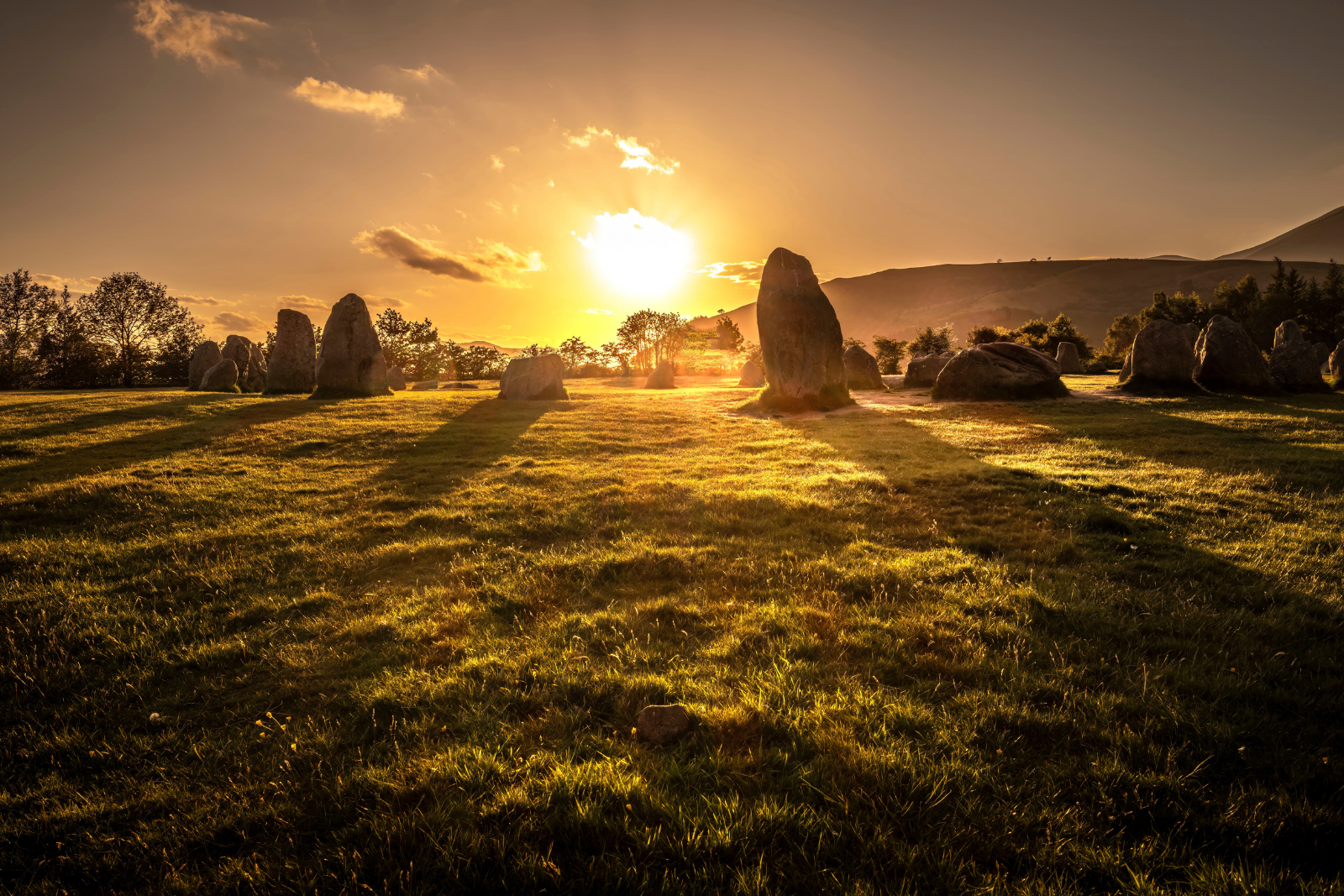 Castlerigg Stone Circle at sunset with the Lake District fells beyond.