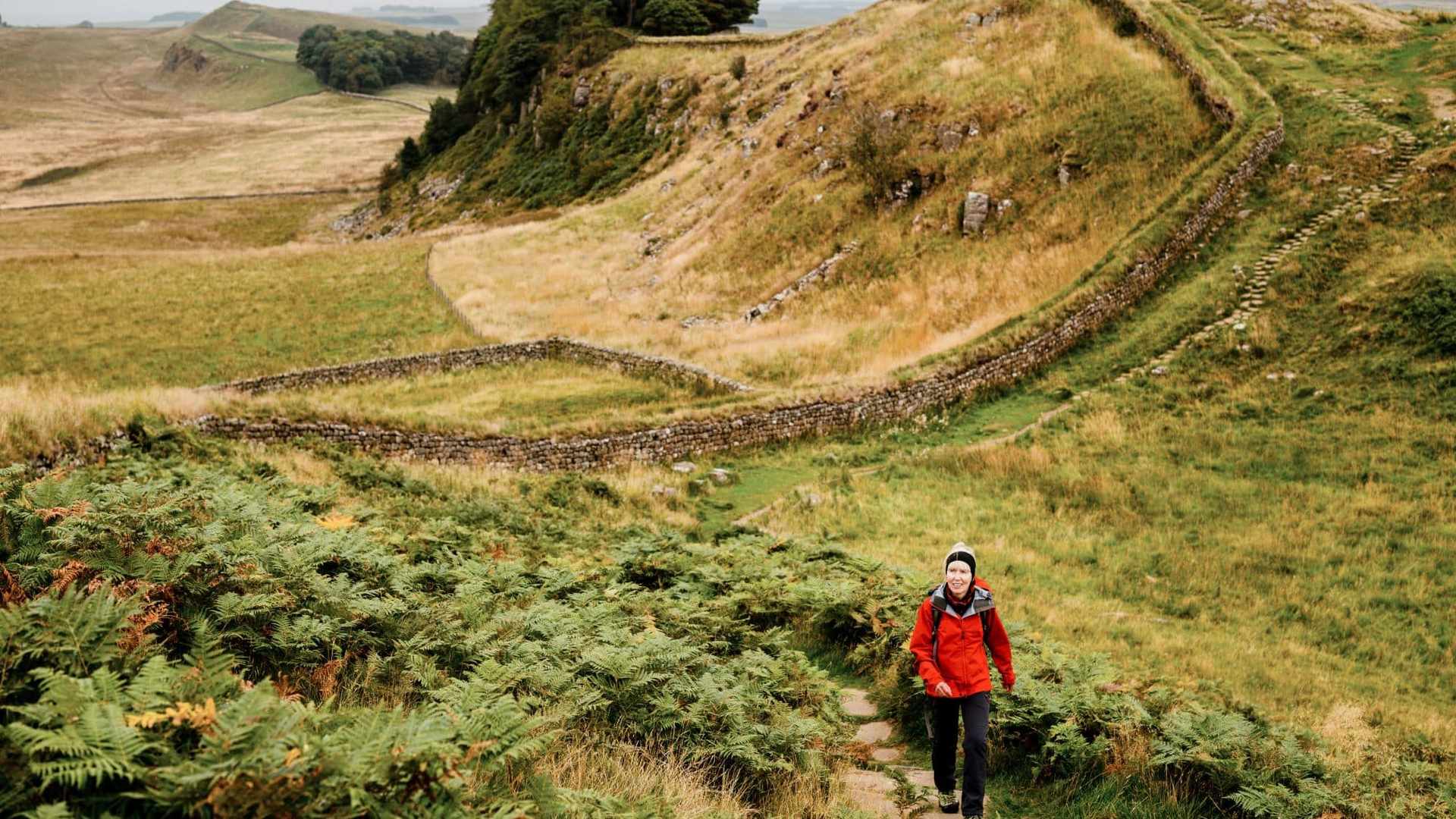 Walker ascending beside Hadrian’s Wall on the Whin Sill escarpment in Northumberland