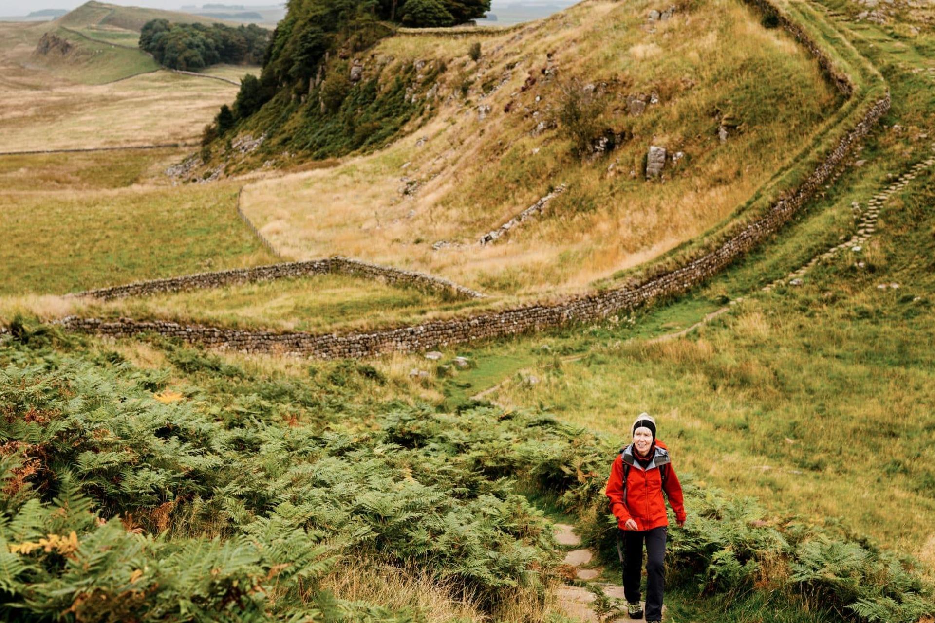 Walker ascending beside Hadrian’s Wall on the Whin Sill escarpment in Northumberland