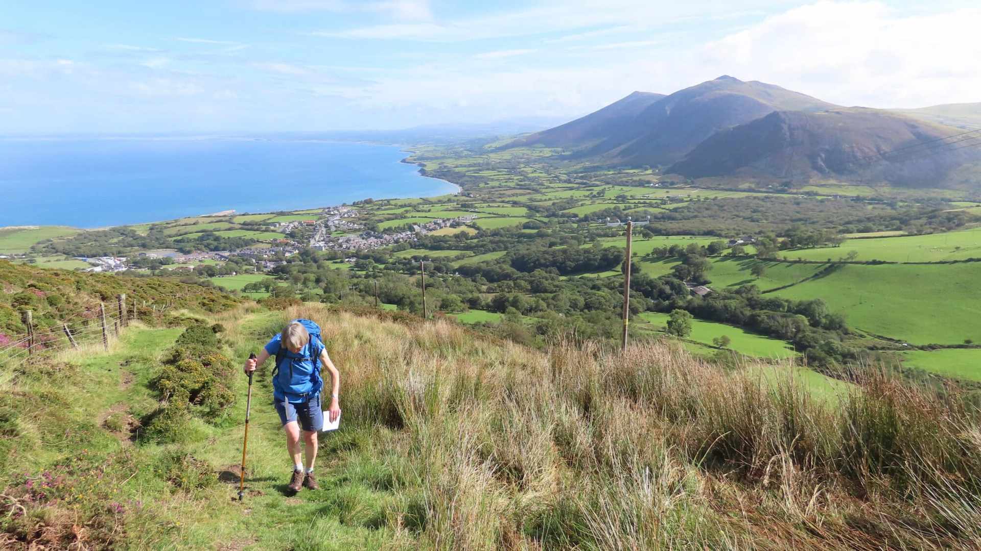 Costal walking path view centred on a female walker climbing a steep path towards the photographer.
