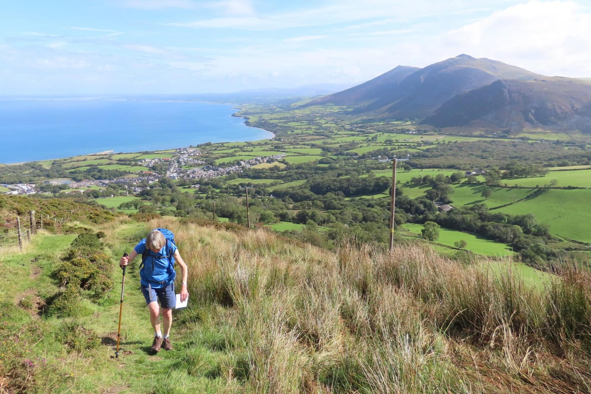 Costal walking path view centred on a female walker climbing a steep path towards the photographer.
