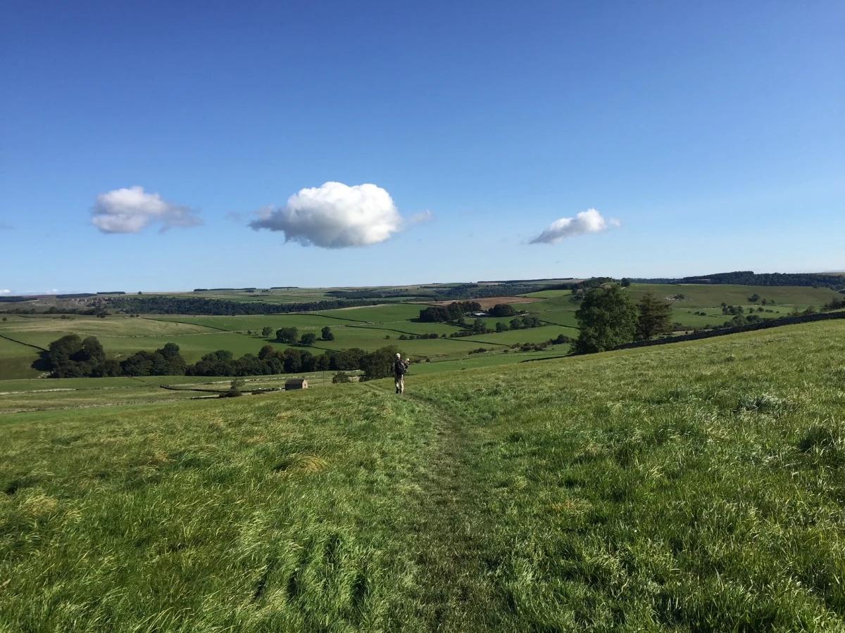 Walker crossing open countryside on the Coast to Coast Walk in northern England