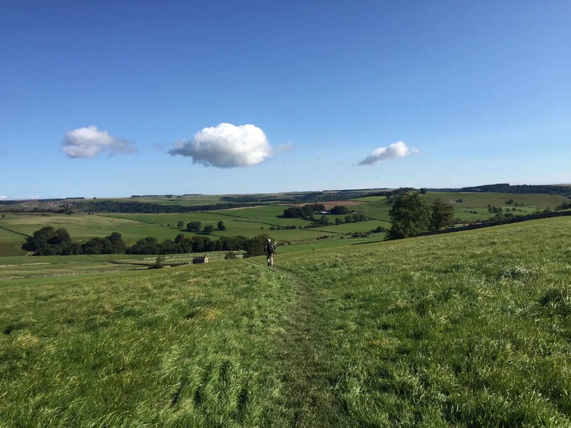 Walker crossing open countryside on the Coast to Coast Walk in northern England