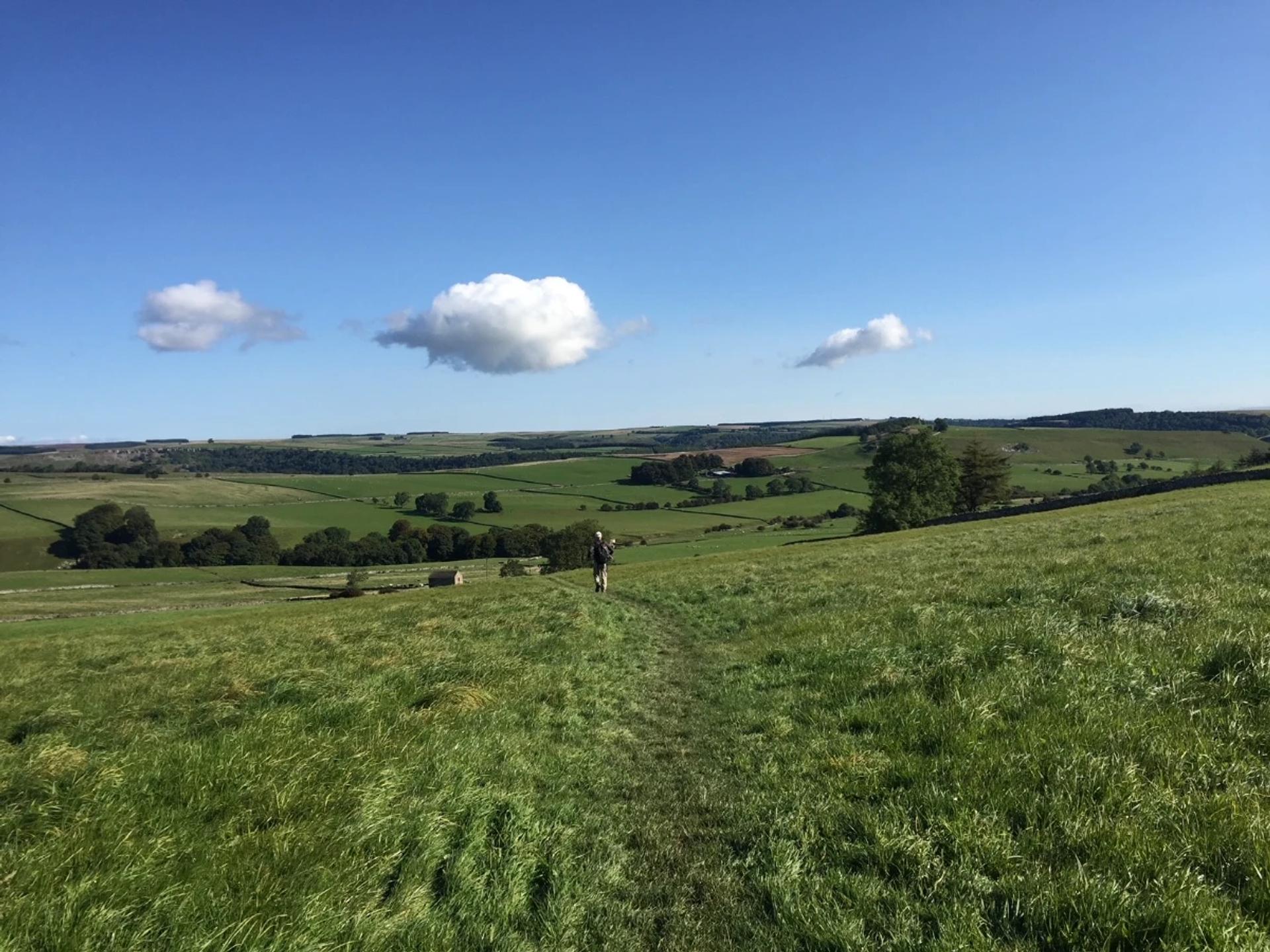 Walker crossing open countryside on the Coast to Coast Walk in northern England