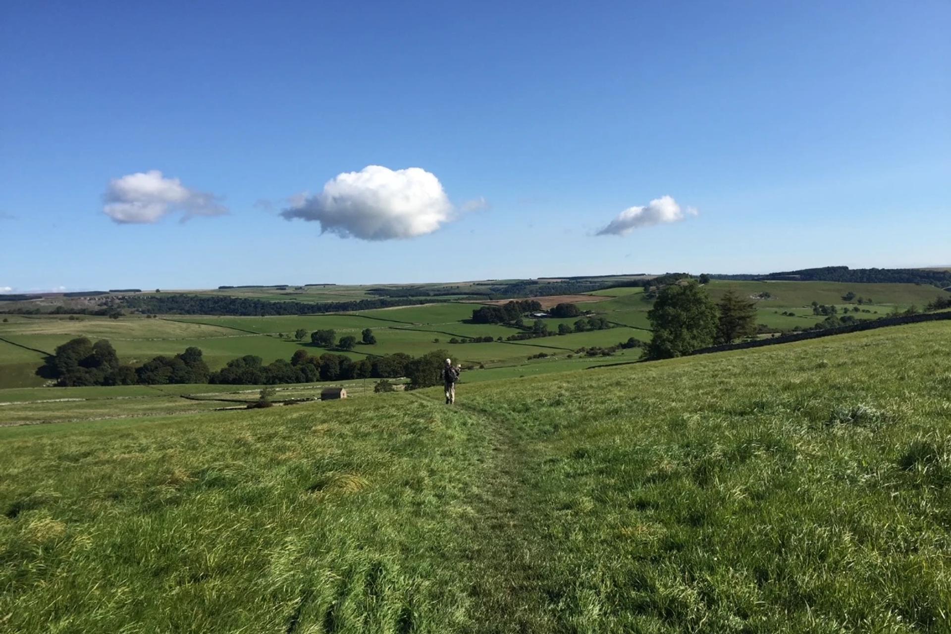 Walker crossing open countryside on the Coast to Coast Walk in northern England