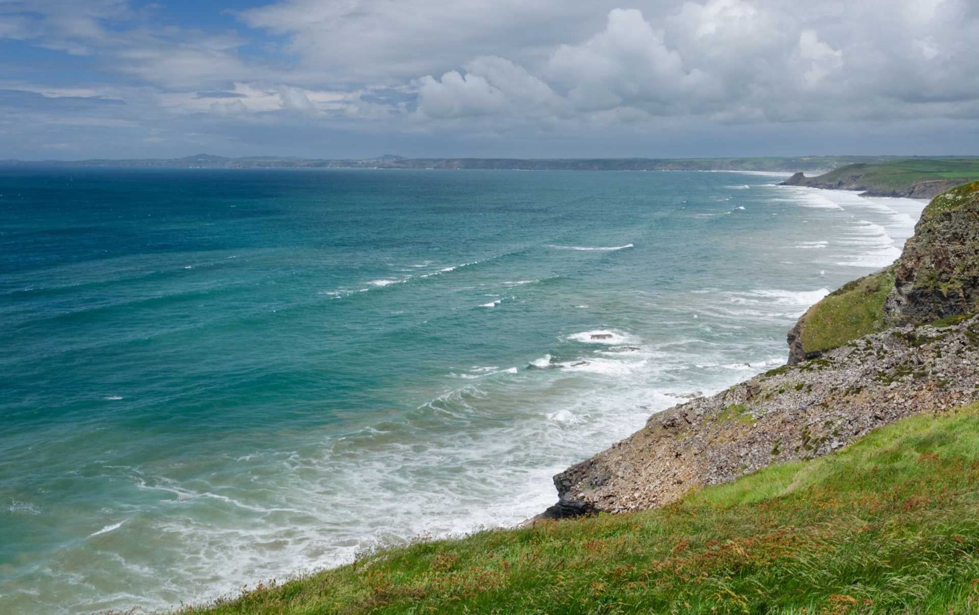 Clifftop view along the Pembrokeshire Coast Path above a long sweep of surf.