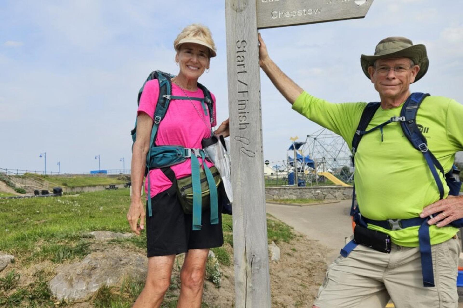 Two people posing for a photograph next to a sign indicating the start/finish of the Wye Valley Way.