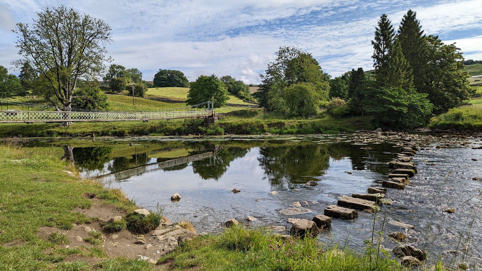 Walker crossing a suspension bridge on the Dales Way in the Yorkshire Dales