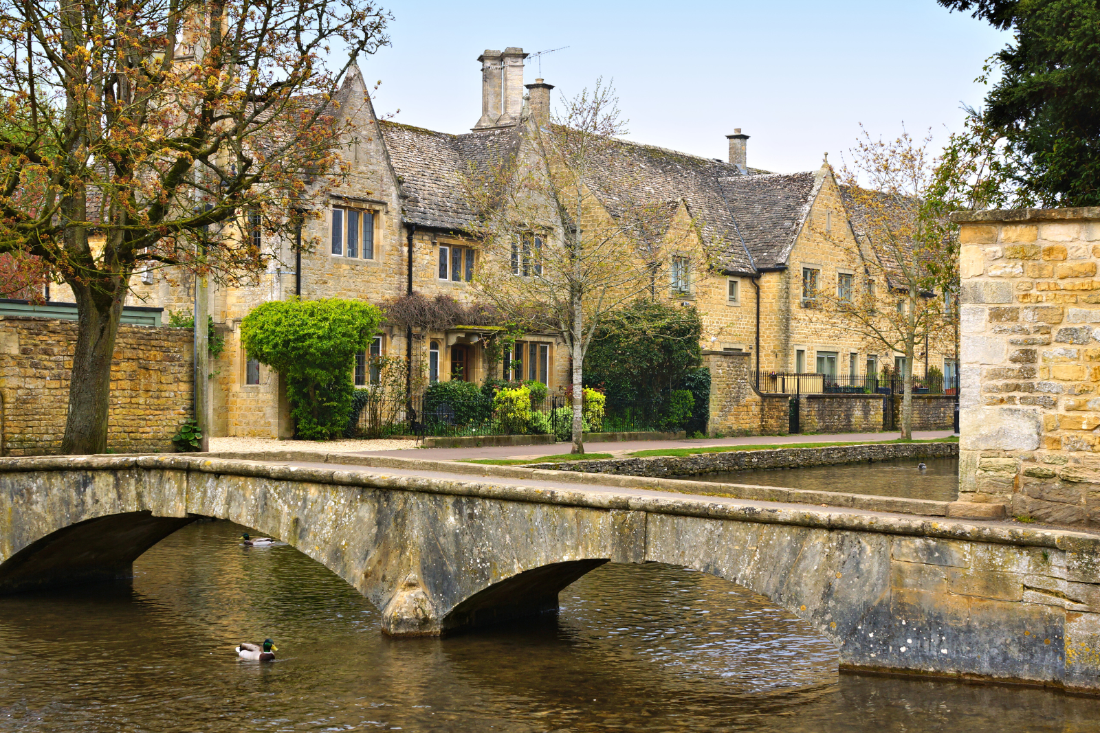 Stone bridge crossing River Windrush with traditional Cotswold cottages in Bourton-on-the-Water.
